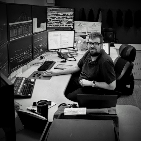 Founder of Hidden Signal demonstrating systems management ata complex operational control desk with multiple railway diagnostic monitors